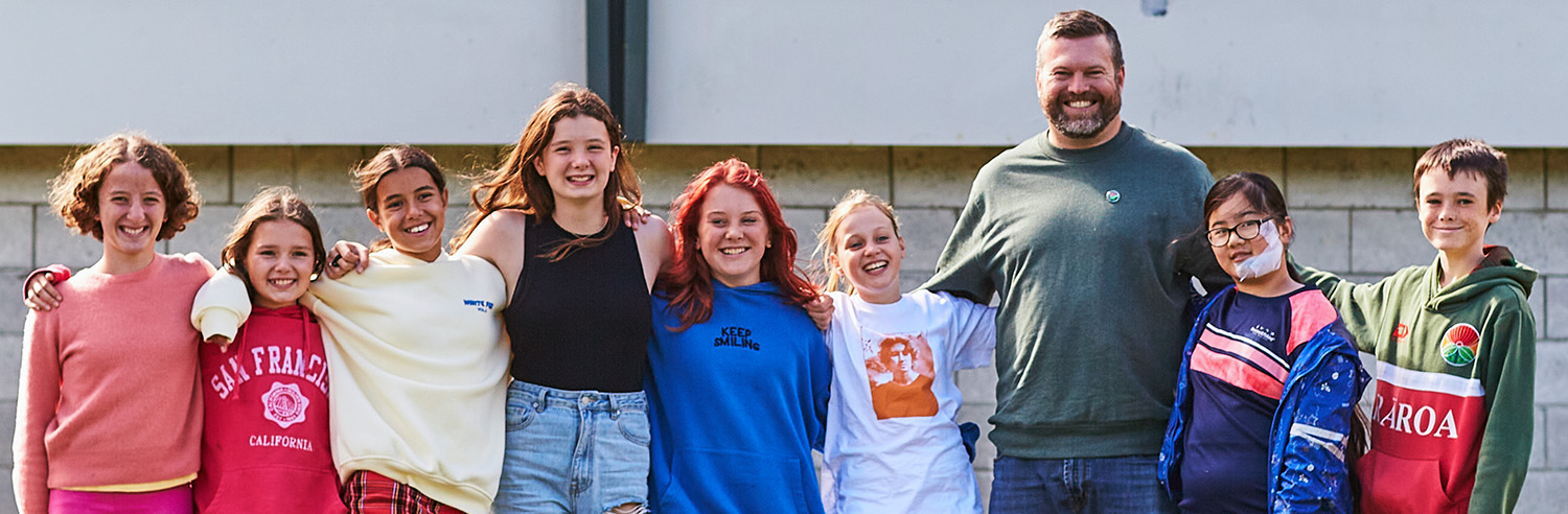 Teacher and students smile at camera.