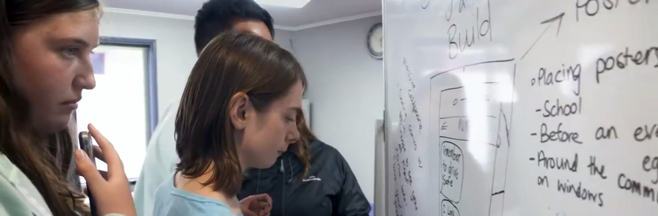 Students develop road safety ideas on a whiteboard.