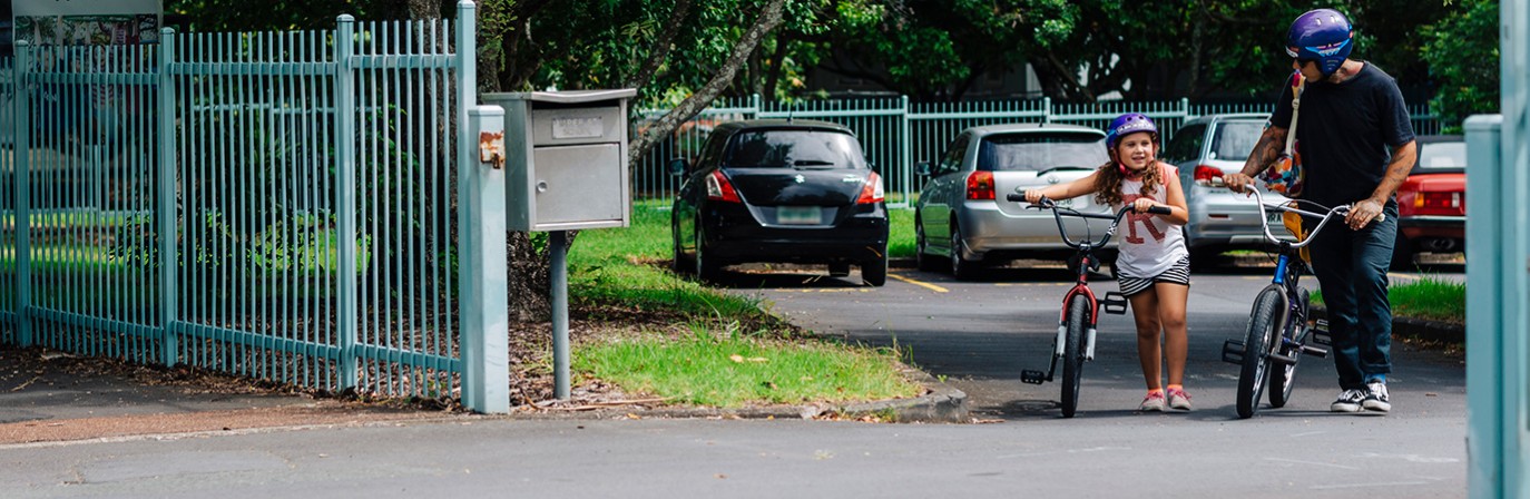 Father and child leave school on bikes.
